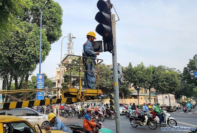 Công nhân lắp đèn tín hiệu mũi tên màu xanh cho xe rẽ phải ở giao lộ Võ Thị Sáu - Bà Huyện Thanh Quan， quận 3， chiều 10/1. Ảnh: Hạ Giang